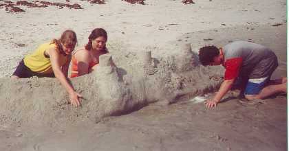 Jess, Courtney, and Aaron build a sand castle wall