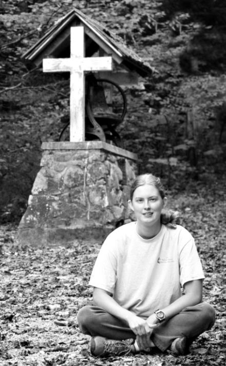 Jess sitting in front of bell at camp
